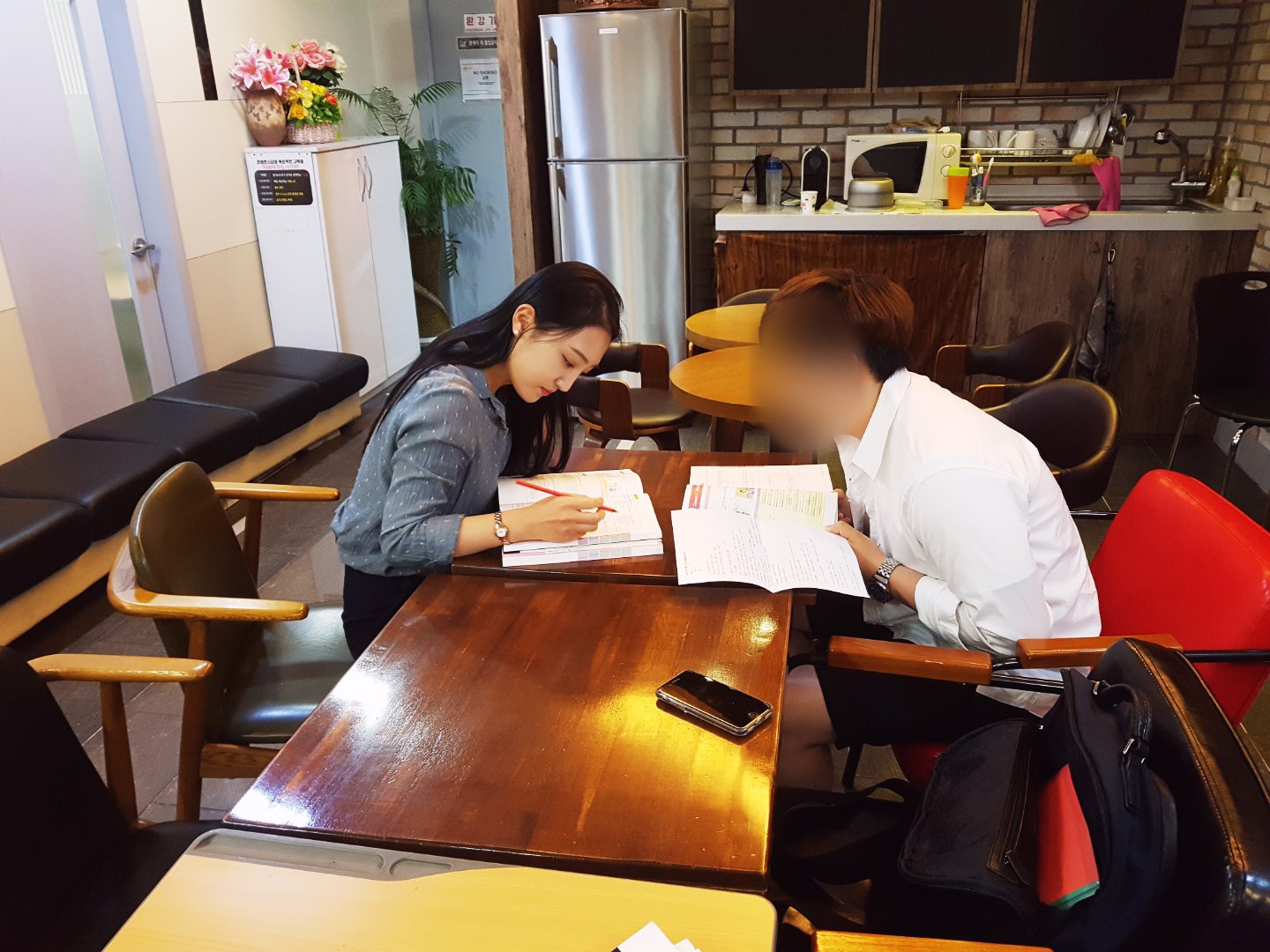 수강생 옆에서 교재에 표시하며 1:1로 설명하는 선생님