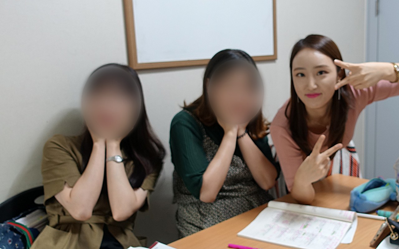 교재를 펴 놓은 책상에서 수강생들과 나란히 앉아 브이를 하는 소피아쌤